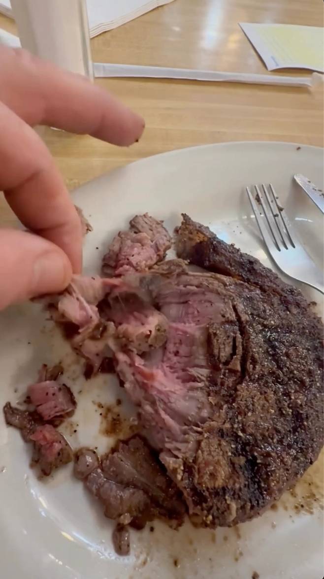 SNS 영상 속 목장주가 식당에서 받은 스테이크를 손으로 찢어 보인다. 그는 “처음부터 이상하다고 느꼈다”며 해당 스테이크가 진짜 필레미뇽이 아니라 고기 조각을 붙여 만든 것 같다고 주장했다. 출처=록킹 W 랜치 인스타그램