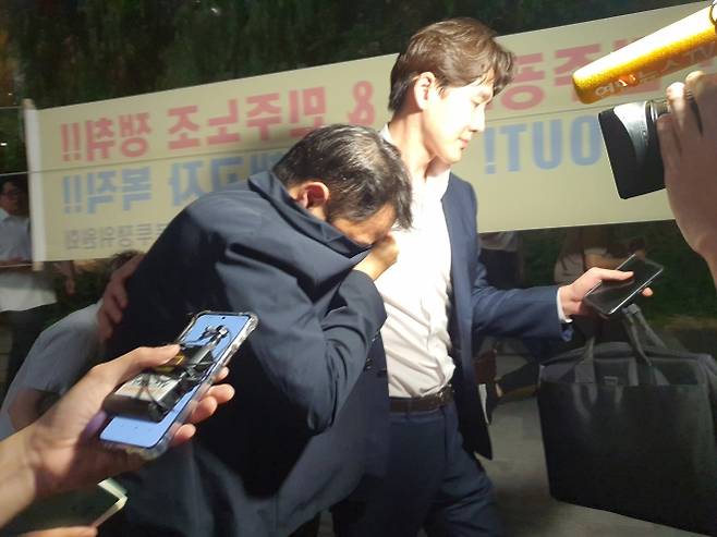 김건희 여사의 오빠 김진우 씨가 28일 오후 김건희 특검팀(특별검사 민중기) 조사를 마치고 옷깃으로 얼굴을 가린 채 변호인 부축을 받으며 취재진을 피해 걸어가고 있다. 2025.7.29 뉴스1