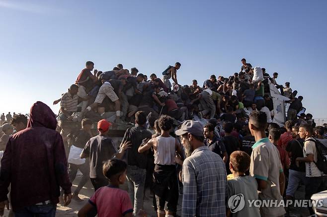 구호품 트럭 (EPA=연합뉴스) 지난 4일(현지시간) 가자지구 남부 모라그회랑의 구호품 배급지점에 트럭이 도착하자 주민들이 이에 올라타고 있다. 2025.8.6 photo@yna.co.kr
