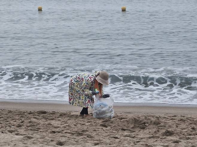지난 9일 새벽 5시쯤부터 김씨(85)가 영덕 장사해수욕장에서 파도에 밀려온 해안가 쓰레기를 허리를 굽혀 맨손으로 봉투에 담고 있다.(영남일보 DB)
