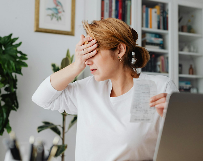 종이 영수증을 들고 반대 손으로 눈을 가리고 있는 여성