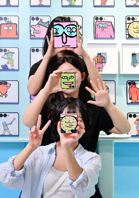 삼성전자가 아티스트 ‘장 줄리앙’과 협업해 대규모 갤럭시 폴더블폰 체험 공간을 다음 달 17일까지 서울 코엑스에서 운영한다고 27일 밝혔다. 방문객들이 ‘갤럭시 Z 폴드7’의 대화면과 ‘갤럭시 Z 플립7’의 커버 디스플레이를 활용해 ‘뉴페이스 셀피’를 촬영하고 있다.(사진=연합뉴스)