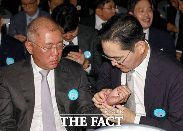 임명식을 앞두고 이재용 삼성전자 회장이 정의선 현대차그룹 회장에게 야광팔찌를 채워주고 있다. /뉴시스