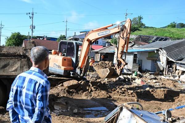 중장비를 동원한 복구작업이 한창인 가운데 마을 주민이 이를 지켜보고 있다. /김구연 기자