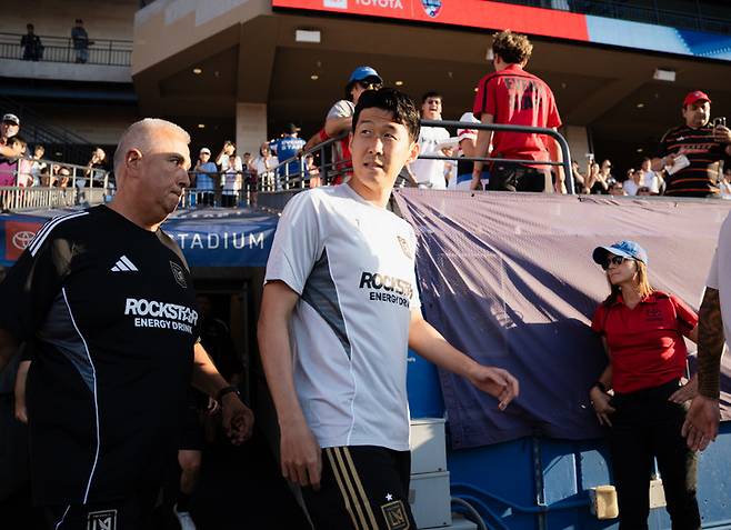 (경기장 도착 후 유니폼으로 갈아 입은 손흥민이 트레이너와 함께 필드 안으로 이동하고 있다)