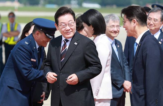 취임 후 처음 미국을 방문한 이재명 대통령이 24일(현지시간) 미국 워싱턴DC 인근 앤드루스 합동기지에 도착해 공군1호기에서 내려 영접 인사로 나온 미국 측 조슈아 킴 대령으로부터 기지 방문 기념 코인을 받아 들고 있다. 연합뉴스