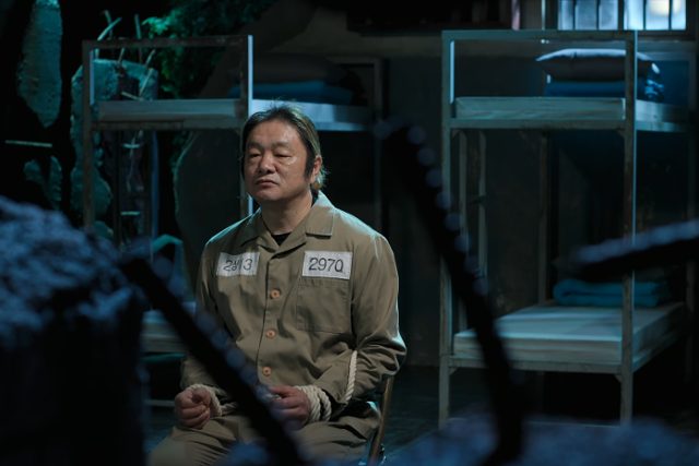 형제복지원에 자신을 넘겼던 경찰에 대한 트라우마로 경찰만 보면 폭언 등을 해 전과 36범이 된 생존자 최승우씨가 형제복지원을 복원한 세트장에서 죄수복을 입고 포승줄에 묶인 채 인터뷰하고 있다. 넷플릭스 캡처