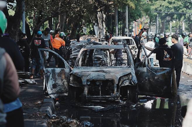29일(현지 시간) 인도네시아 자카르타에서 시민들이 전날 국회의원들에게 지급되는 과도한 수당에 항의하는 시위 중 불에 탄 차량 잔해를 살펴보고 있다. 2025.08.29 자카르타=AP/뉴시스