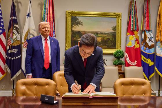 이재명 대통령이 지난달 25일(현지시간) 미국 워싱턴 DC 백악관에서 도널드 트럼프 미국 대통령이 지켜보는 가운데 방명록을 작성하고 있다. 뉴스1