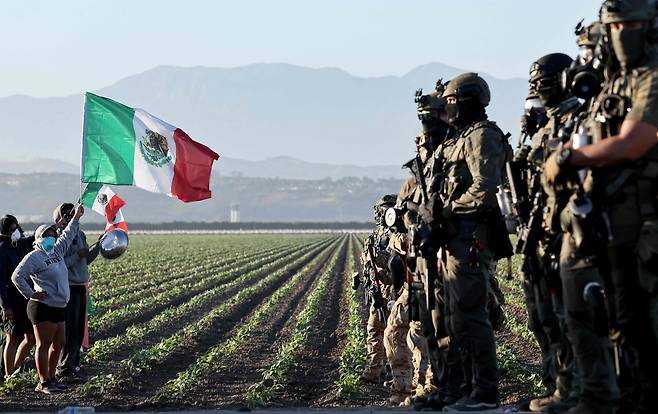 지난 7월 10일(현지 시각) 미국 캘리포니아주 카마릴로 인근 대마초 농장에서 연방 요원들이 ICE의 이민 단속에 항의하는 시위대를 막아 섰다./ 게티이미지 AFP 연합뉴스