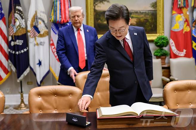 지난 8월 25일(현지시간) 이재명 대통령이 한미정상회담에 앞서 미 백악관 루스벨트룸에서 방명록에 서명하려고 펜을 잡으려는 순간 도널드 트럼프 미국 대통령이 뒤에서 의자를 당겨 주고 있다. (백악관 제공. 재판매 및 DB금지) 2025.9.1/뉴스1 ⓒ News1 류정민 특파원