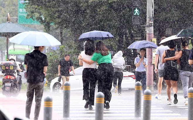 소나기가 내린 지난달 25일 서울 종로구 경복궁을 찾은 관광객들이 우산을 쓰고 걷고 있다. /뉴스1