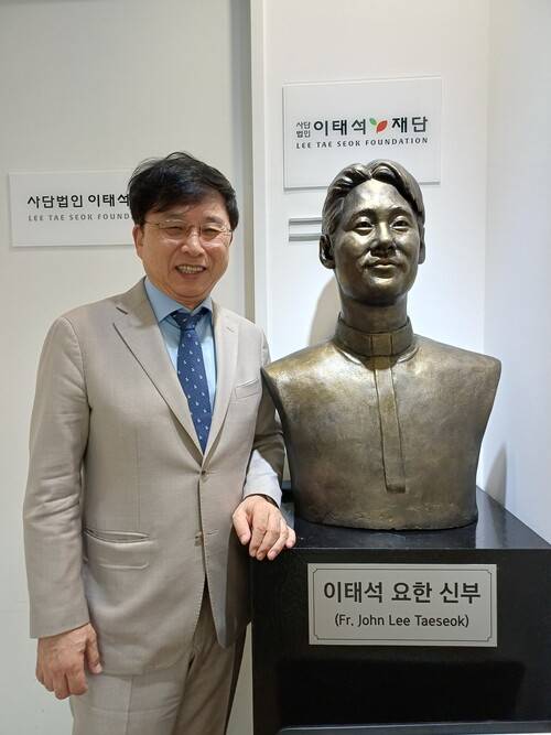 구수환 이태석재단 이사장이 재단 사무실 앞의 이태석 신부상 옆에서 사진 포즈를 취하고 있다. 김아리 객원기자