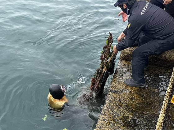 8일 오후 2시 제주시 조천읍 조천포구에서 해녀가 수거한 트라이포드를 해경대원에게 전달하고 있다. 최충일 기자
