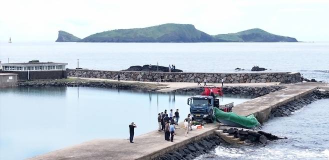 해경과 경찰 등 관계자들이 8일 오전 제주시 한경면 용수리 해안가에서 이날 오전 발견된 미확인 보트를 조사해 인양하려 하고 있다. 해당 보트는 중국인 밀입국자들이 탔던 것으로 확인됐다. 연합뉴스