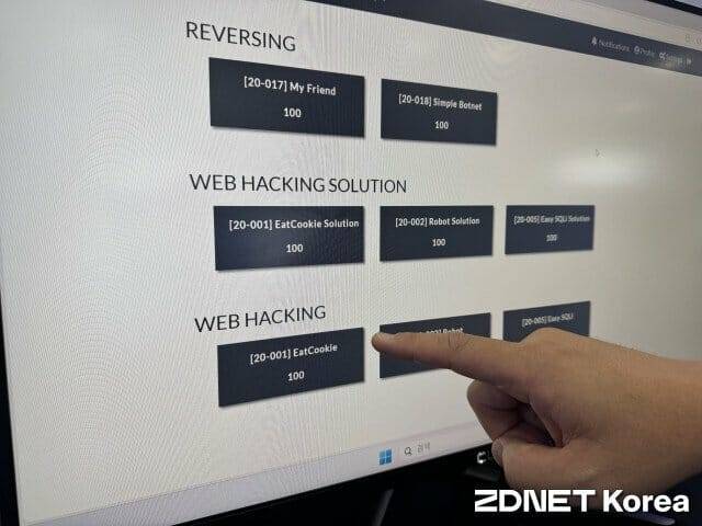 기자가 풀어야 하는 문제를 가리키고 있는 대회 관계자.