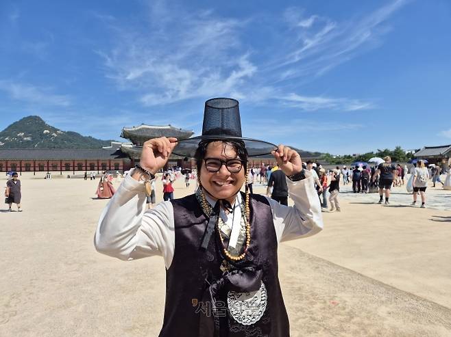 14일 서울 종로구 경복궁에서 한 외국인 관광객이 넷플릭스 애니메이션 영화 ‘케이팝 데몬 헌터스’에 등장하는 저승사자 콘셉트의 보이그룹 사자 보이스를 따라 검은색 한복과 갓을 쓴 모습.