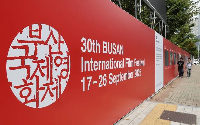 제30회 부산국제영화제(BIFF) 개막을 이틀 앞둔 15일 부산 해운대구 영화의전당 앞에 설치된 포스터 앞으로 시민이 지나가고 있다. /연합