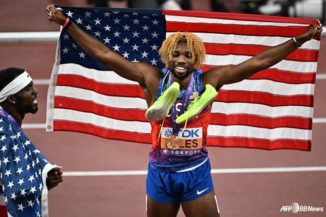 노아 라일스가 19일 일본 도쿄국립경기장에서 열린 2025 세계선수권 남자 200m 결선에서 금메달을 목에 걸고 미국 국기를 펼쳐보이고 있다. /AFPBBNews=뉴스1