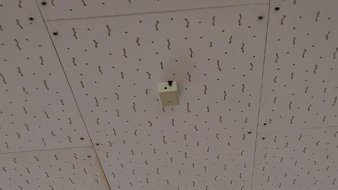 요양원 건물 내부, 천장에 붙어 있는 작고 하얀 물체. 직원들은 이 물체가 ‘불법 도청 장치’라고 주장합니다.