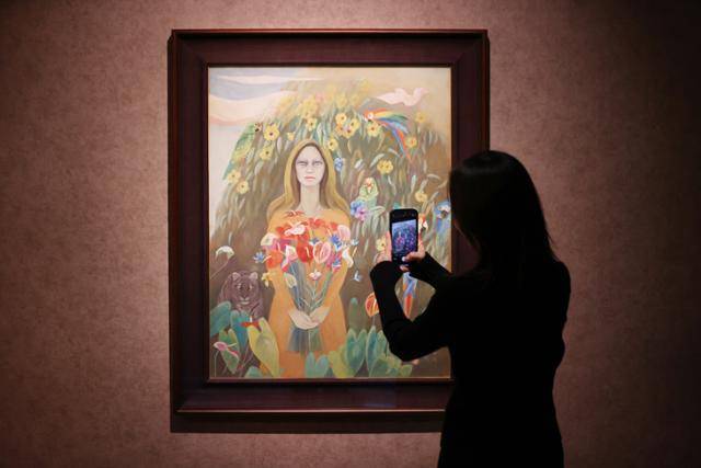 23일 서울 종로구 석파정 서울미술관에서 열린 천경자 작고 10주기 특별기획전 '내 슬픈 전설의 101페이지'에서 참석자가 '알라만다의 그늘Ⅰ'을 살펴보고 있다. '알라만다의 그늘'은 천경자 작품의 주요 주제로 꼽히는 여인과 꽃, 동물 등 다양한 소재가 화폭에 빈틈없이 들어찬 작품이다. 연합뉴스
