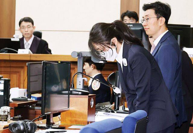 검은 정장 차림에 흰색 마스크를 쓴 김건희 여사가 24일 서울 서초구 서울중앙지방법원에서 진행된 첫 재판에서 고개를 숙이고 있다. 김 여사는 정치자금법 및 자본시장법 위반 등 혐의로 구속돼 재판에 넘겨졌다. 사진공동취재단