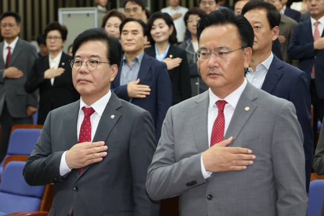 국민의힘 송언석(왼쪽) 원내대표와 유상범 원내수석부대표를 비롯한 의원들이 24일 서울 여의도 국회에서 열린 긴급 의원총회에서 국기에 경례하고 있다. 연합뉴스