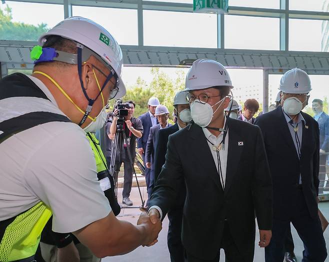 Prime Minister Kim Min-seok (center) greets a construction worker during a site visit to the APEC exhibition hall in Gyeongju, North Gyeongsang Province, on Friday, checking on progress ahead of the 2025 summit. (Yonhap)