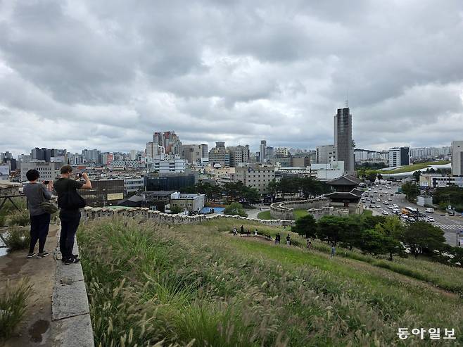 외국인 관광객 부부가 낙산공원 성곽길을 걷다 동대문과 DDP가 어우러지는 풍경을 바라보며 사진을 찍고 있다.