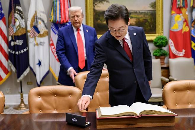 (워싱턴=뉴스1) 류정민 특파원 = 지난 8월 25일(현지시간) 이재명 대통령이 한미정상회담에 앞서 미 백악관 루즈벨트룸에서 방명록에 서명하려고 펜을 잡으려는 순간 도널드 트럼프 미국 대통령이 뒤에서 의자를 당겨 주고 있다. 2025.08.31(백악관 제공. 재판매 및 DB금지) Copyright (C) 뉴스1. All rights reserved. 무단 전재 및 재배포, AI학습 이용 금지. /사진=(워싱턴=뉴스1) 류정민 특파원