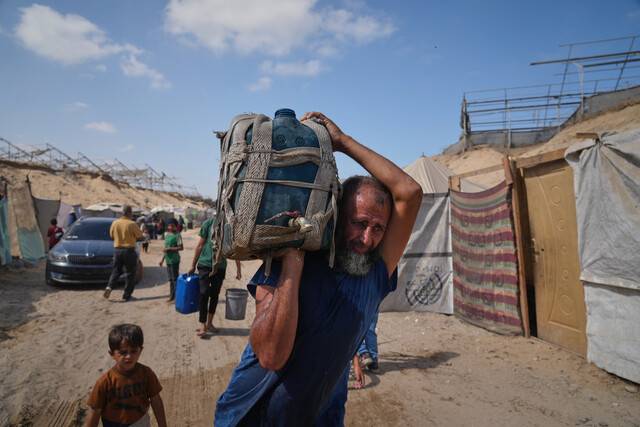 29일(현지시각) 팔레스타인 가자지구 남부 무와시 지역에서 한 피란민 남성이 배급받은 식수를 담은 물통을 이고 가고 있다. AP 연합뉴스