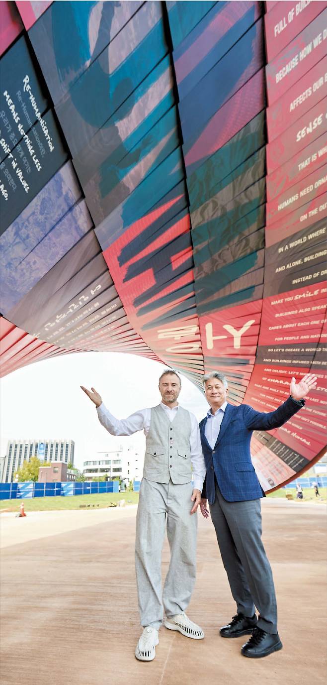 동국제강그룹‘서울도시건축비엔날레’가 열리는 서울 종로구 열린송현녹지광장에서 지난달 23일 토머스 헤더윅(왼쪽) 비엔날레 총감독과 장세욱 동국제강그룹 부회장이 초대형 철강 건축물 ‘휴머나이즈 월’ 아래에서 포즈를 취하고 있다. 꽈배기 모양의 이 조형물은 동국제강그룹이 제작, 후원한 컬러 강판(鋼板) 1428장을 유연하게 비틀어 조각보처럼 이어 붙여 만들었다.