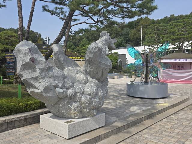 크리스찬메모리얼파크 분수대 앞 광장에 최중갑 작가의 ‘새벽닭’(왼쪽, 310×170×260cm, 무게 8톤, 고흥석)과 류지연 작가의 ‘별을 꿈꾸는 나비’(120×120×250cm, 스테인리스 스틸, 다이크로익 필름)가 설치돼 있다. 크리스찬메모리얼파크 제공