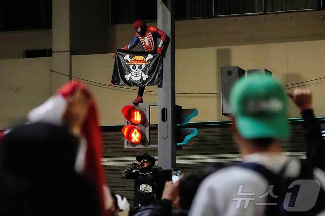 9월 28일(현지시간) 페루 리마에서 스파이더맨 복장을 한 시위 참가자가 만화 '원피스'의 '밀짚모자 해적단' 깃발을 들고 신호등 위에 올라서 있다. 2025.09.28. ⓒ 로이터=뉴스1 ⓒ News1 윤다정 기자