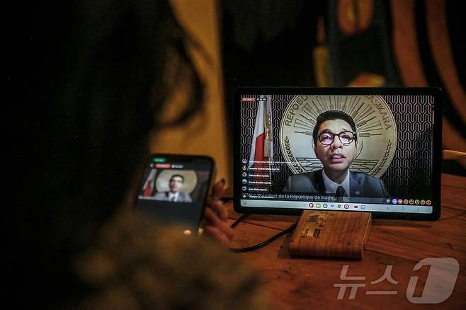 13일(현지시간) 마다가스카르 수도 안타나나리보의 한 주민이 자택에서 마다가스카르 대통령 안드리 라조엘리나의 대국민 연설을 대통령실 공식 페이스북 페이지를 통해 시청하고 있다. 라조엘리나 대통령은 프랑스 군용기를 타고 해외 도피했다. 사임 요구가 거세지는 가운데 실종 상태였던 라조엘리나 대통령의 연설은 많은 관심을 모았으나, 무장 군인들이 국영 방송 장악을 시도하면서 두 차례나 지연됐다.ⓒ AFP=뉴스1