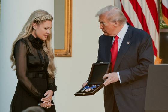 도널드 트럼프 미국 대통령(오른쪽)이 14일(현지시간) 워싱턴 DC 백악관 로즈가든에서 지난달 암살된 청년 보수단체 운동가 찰리 커크에게 사후 수여하는 자유의 메달을 그의 부인 에리카에게 전달하고 있다. 로이터=연합뉴스