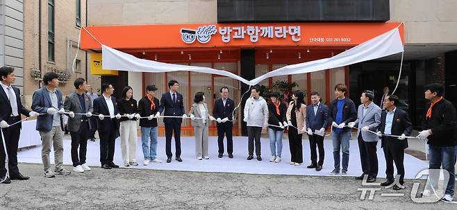 16일 진행된 ‘밥과함께라면’ 4호점 개소식에서 참석자들이 간판 제막식을 하고 있는 모습.(용인YMCA 제공)