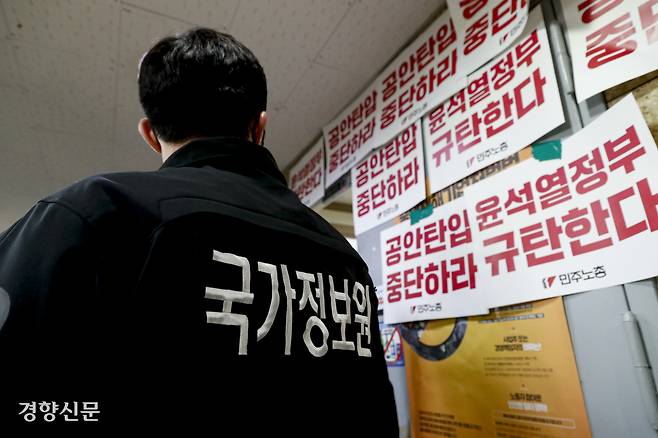 2023년 1월 서울 정동 민주노총 사무실을 압수수색하러 온 국가정보원 관계자가 ‘공안탄압 중단하라’고 쓰인 종이를 보고 있다. 문재원 기자
