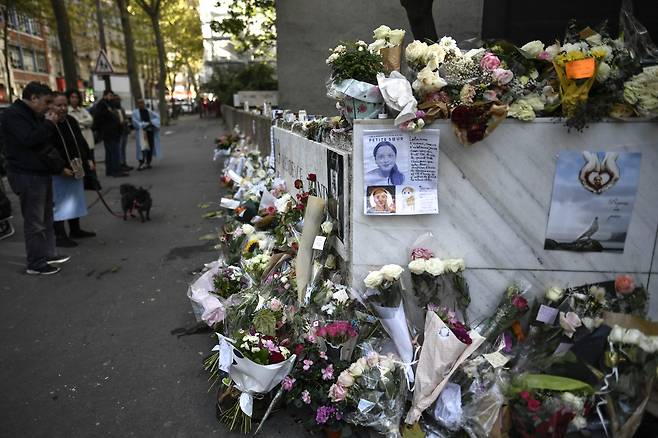 지난 2022년 10월 20일(현지시간) 파리 19구에서 트렁크 안에서 시신이 발견된 12세 여학생 롤라가 거주하던 건물 앞에 놓인 꽃들 근처를 보행자들이 지나가고 있다. AFP=연합뉴스
