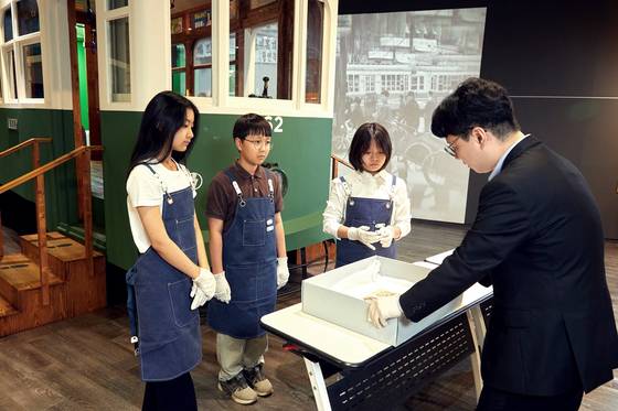 이상일 학예사와 함께 해리 라이스 보스트위크 앨범을 살펴보는 소중 학생기자단.