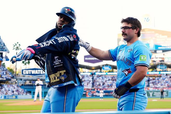 토론토의 데이비스 슈나이더(오른쪽)가 30일 LA 다저스와의 월드시리즈 5차전에서 1회초 선두타자로 홈런을 친 자신에 이어 2번 타자로 홈런을 치고 돌아온 블라디미르 게레로 주니어에게 ‘홈런 재킷’을 입혀주고 있다. 월드시리즈 경기를 두 타자 연속 홈런으로 시작한 건 이들이 처음이다. 로스앤젤레스=AP 뉴시스