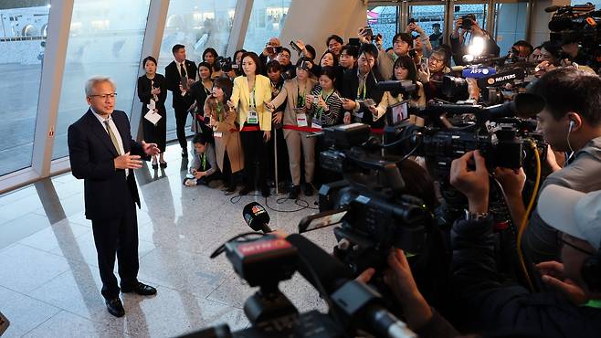Nvidia CEO Jensen Huang answers reporters’ questions at the entrance of the Gyeongju Arts Center in North Gyeongsang Province before attending a press conference on Friday. (Im Se-jun/The Korea Herald)