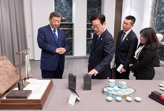 (경주=연합뉴스) 이재명 대통령과 시진핑(왼쪽) 중국 국가주석이 1일 경북 소노캄 호텔에서 국빈만찬 전 서로를 위해 준비한 선물을 보고 있다. 시 주석이 선물한 샤오미 휴대전화를 이 대통령이 만져보고 있다.