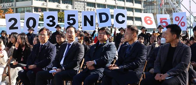 27일 서울 광화문광장에서 김성환 기후에너지환경부 장관(앞줄 오른쪽에서 세번째)이 참석한 제3회 지구하다 페스티벌 개막식에서 기후위기비상행동 회원들이 2035년 국가 온실가스 감축목표(NDC) 65% 수립을 촉구하는 피켓을 들어보이고 있다. /뉴시스