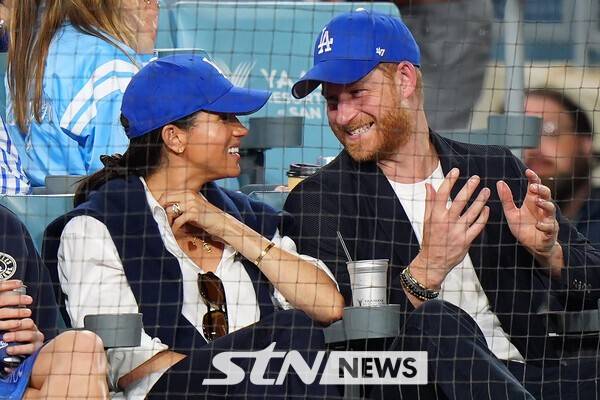 해리 영국 왕자(우측)가 아내 메건 마클과 지난달 30일(한국시각) 미국 로스앤젤레스주 다저스타디움에서 열린 LA다저스와 토론토 블루제이스의 월드시리즈 4차전에서 다저스 모자를 쓰고 경기를 관람하는 모습이 잡혔다. /사진=뉴시스(AP)