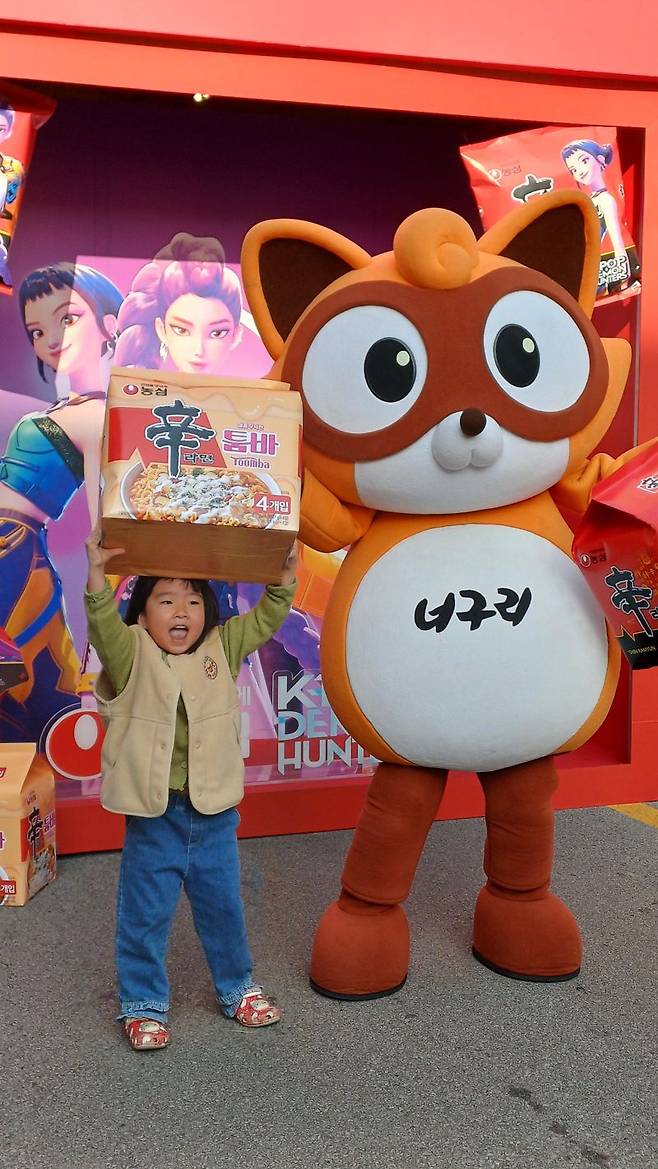 지난 7일 경상북도 구미시에서 열린 '2025 구미라면축제'에 참석한 어린이가 농심 너구리 캐릭터와 기념촬영을 하고 있다. 사진=이환주 기자