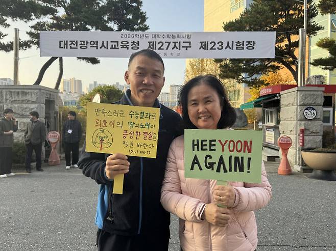 수능일인 13일 딸 희윤 씨를 고사장에 들여보낸 뒤 응원메시지가 적힌 팻말을 들고 사진을 찍고 있는 부모님. (사진=임효인 기자)