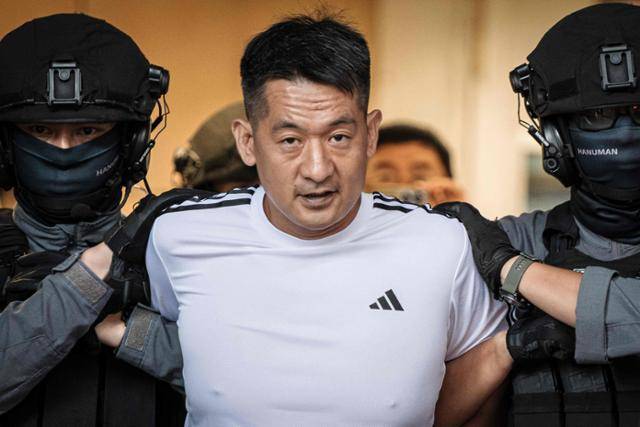 중국 온라인 사기 거물 서즈장이 12일 태국 방콕에서 중국 당국 관계자에게 인계되고 있다. 방콕=AFP 연합뉴스