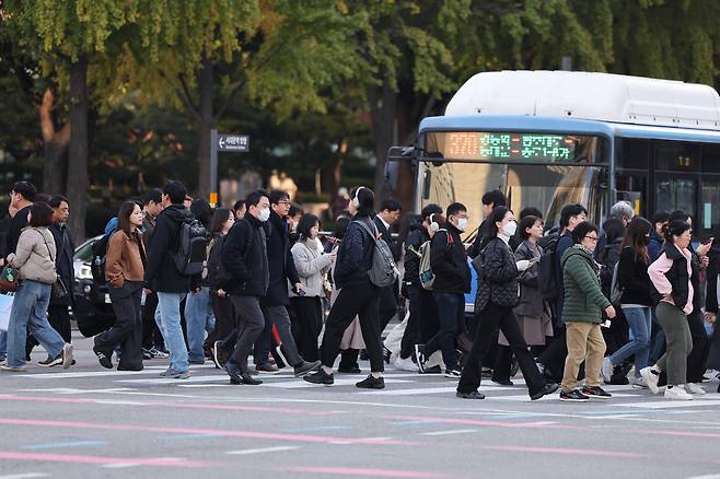 As morning temperatures dropped and the daily temperature gap widened on Nov. 4, people wearing thick coats cross a street near Gwanghwamun Square in central Seoul. (Yonhap)