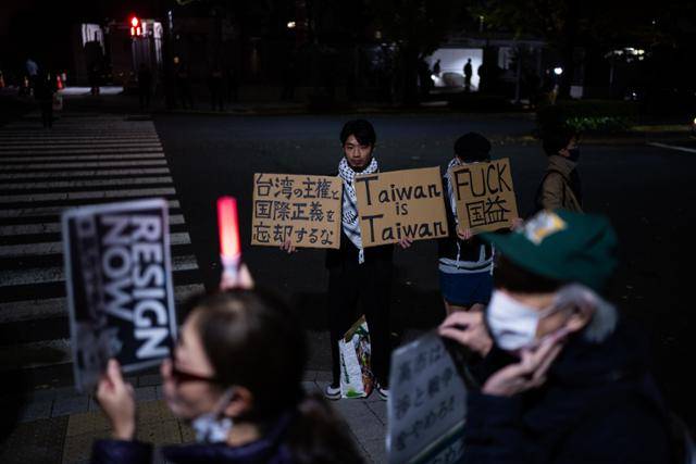 21일 밤 일본 도쿄 총리실 앞에서 시위대가 다카이치 사나에 총리의 대만 관련 발언에 반대하며 시위하는 가운데 한 남성이 대만을 지지하는 손팻말을 들고 있다. AP뉴시스